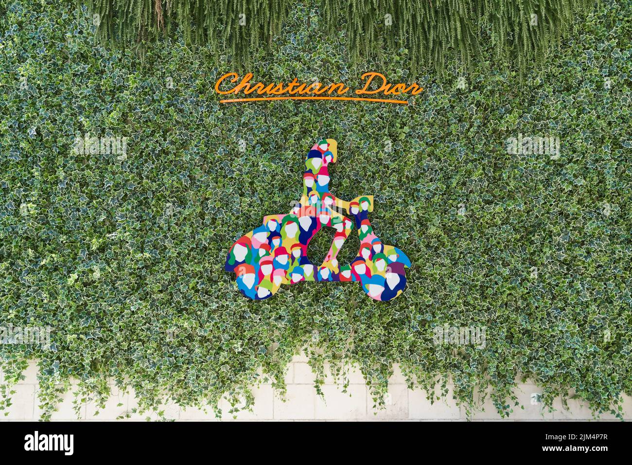 Christian Dior brand sign on a wall overgrown with ivy Stock Photo