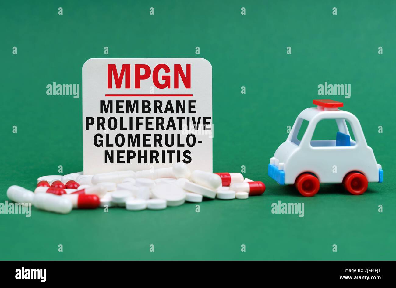 Medical concept. On a green surface, an ambulance, pills and a white sign with the inscription - membrane proliferative glomerulonephritis Stock Photo
