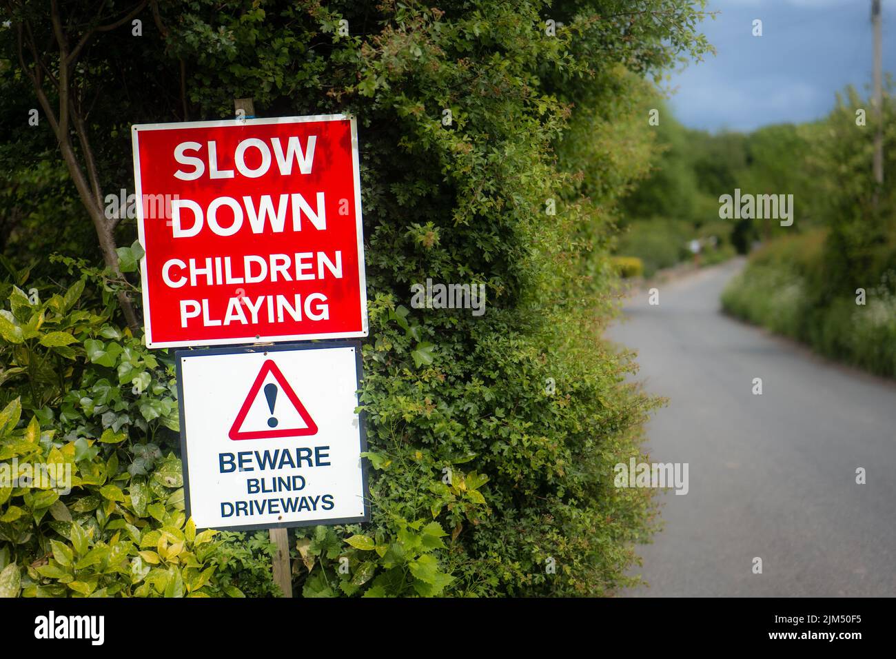 Slow Down Children Playing red warning road sign on a country lane. UK. Stock Photo