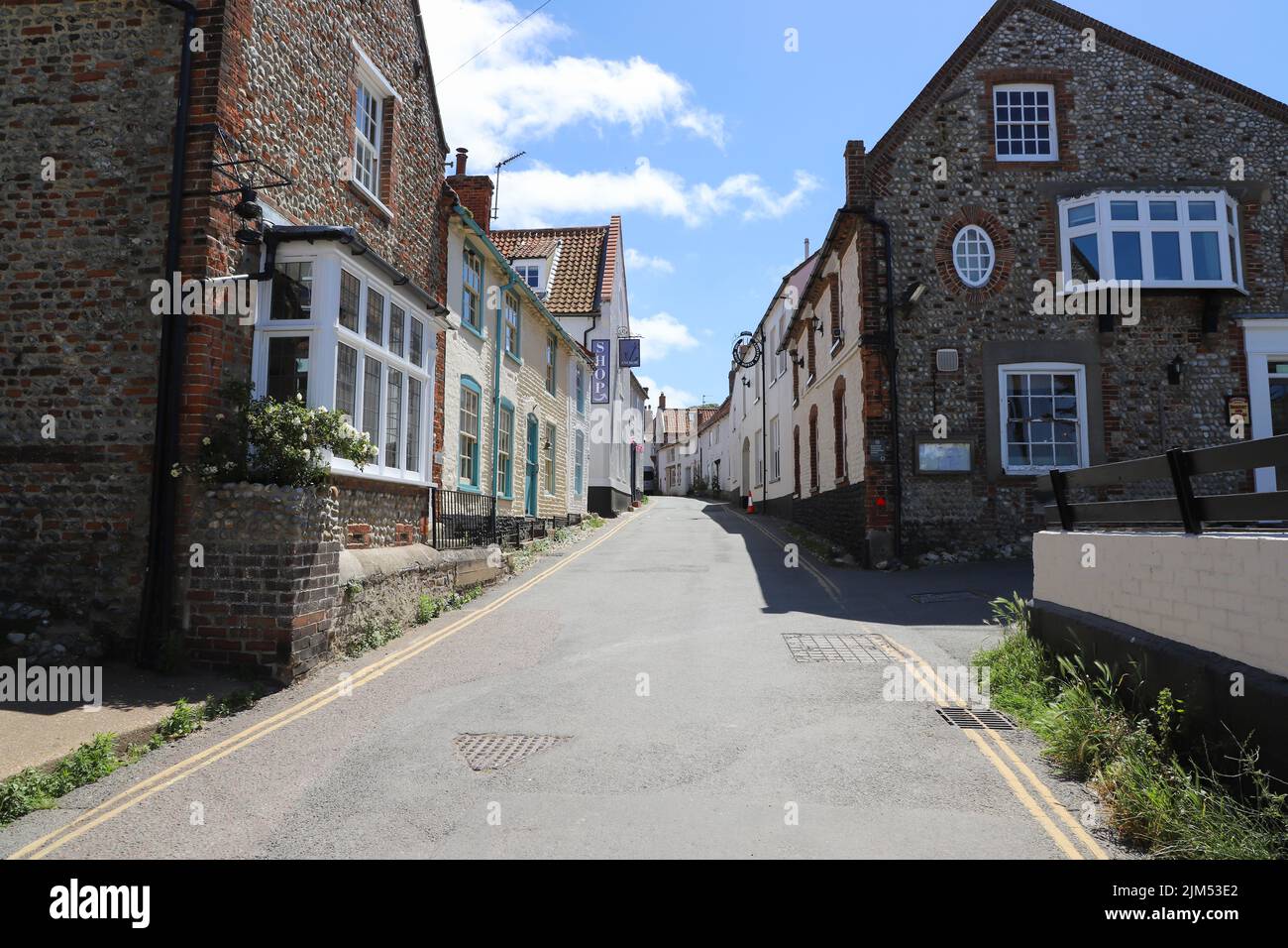 Traditional Flint built houses and shops in the High Street of Blakeney, North Norfolk in the UK Stock Photo