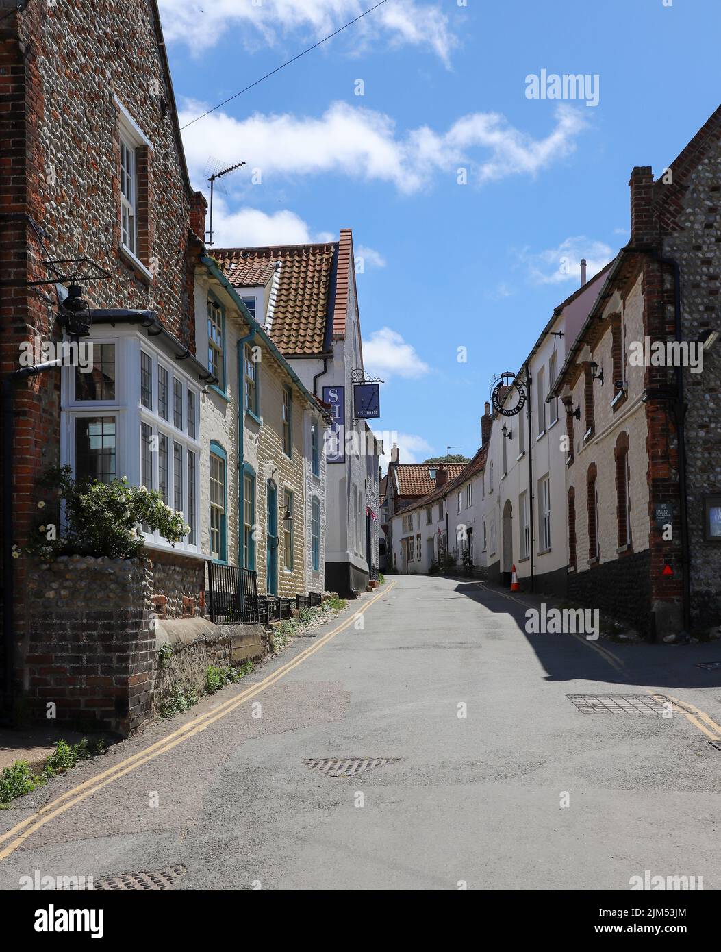 Traditional Flint built houses and shops in the High Street of Blakeney, North Norfolk in the UK Stock Photo