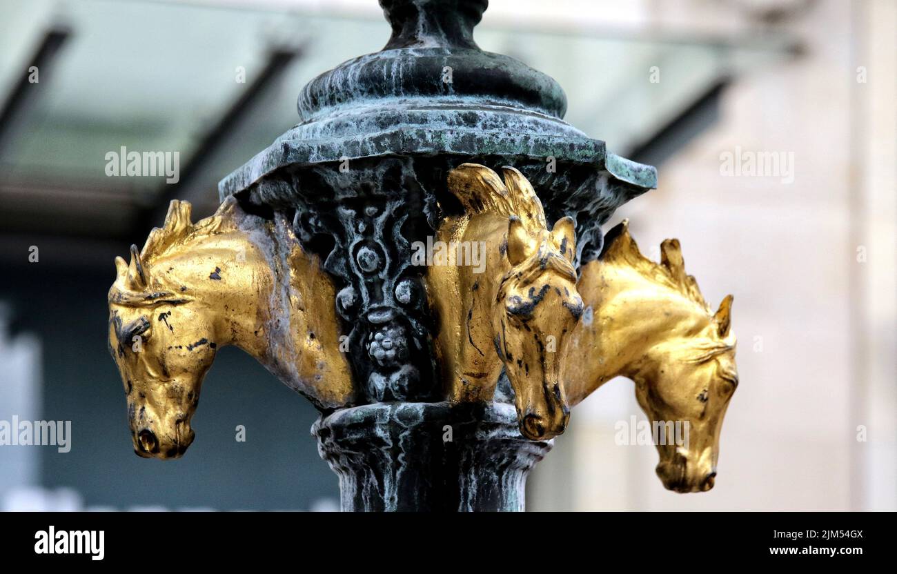 in the past, this type of fountain was used to water the horsesthe close-up shows the upper part of the fountain with golden horse heads Stock Photo