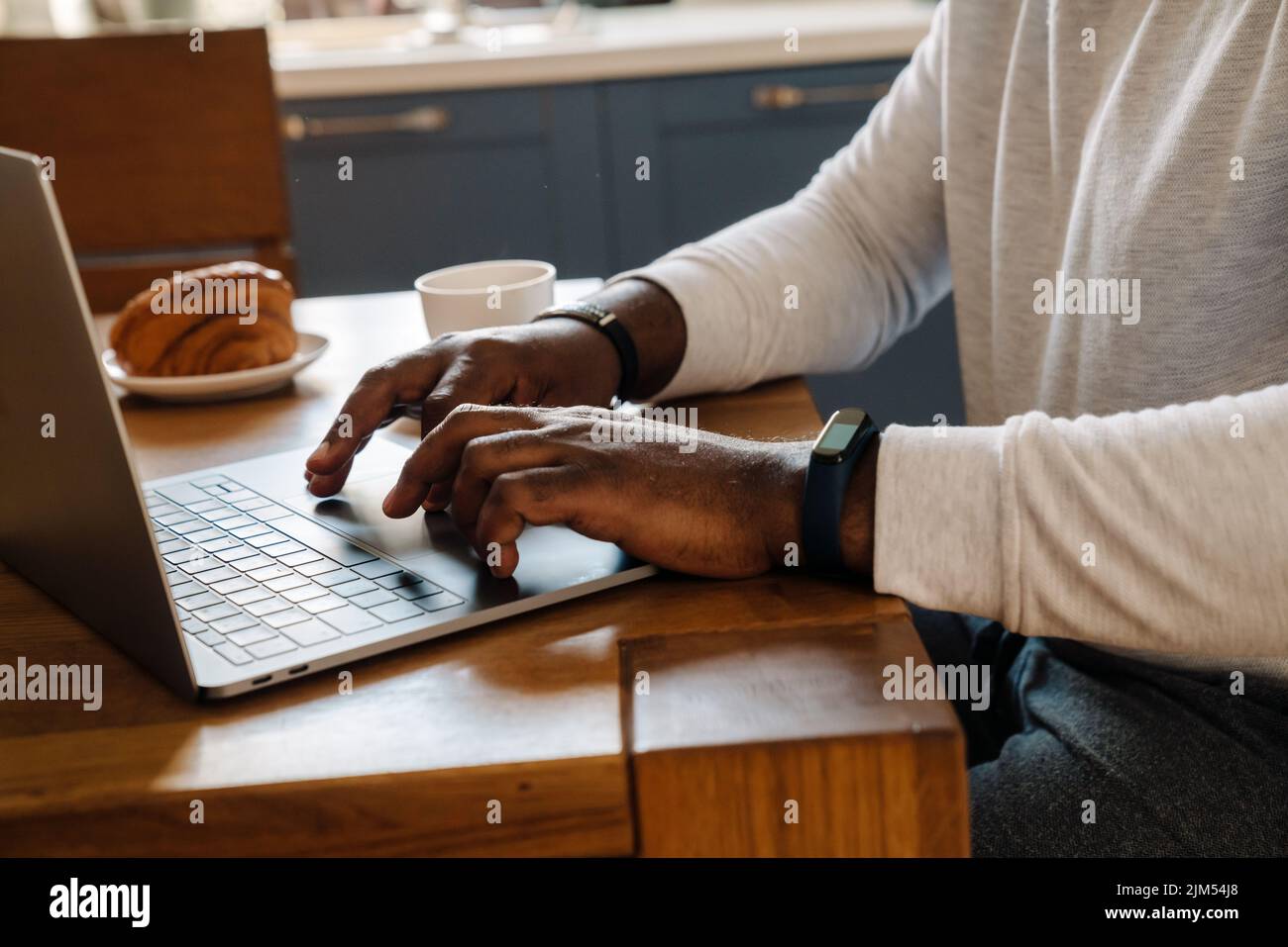 Black man working with laptop while having breakfast at home Stock Photo