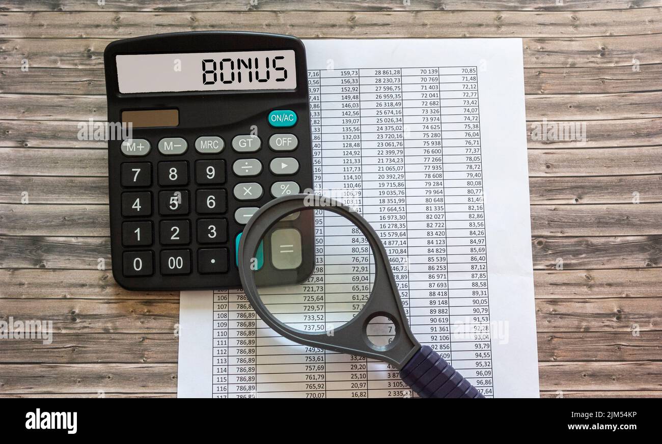 Word BONUS on the display of a calculator on financial documents. Stock Photo