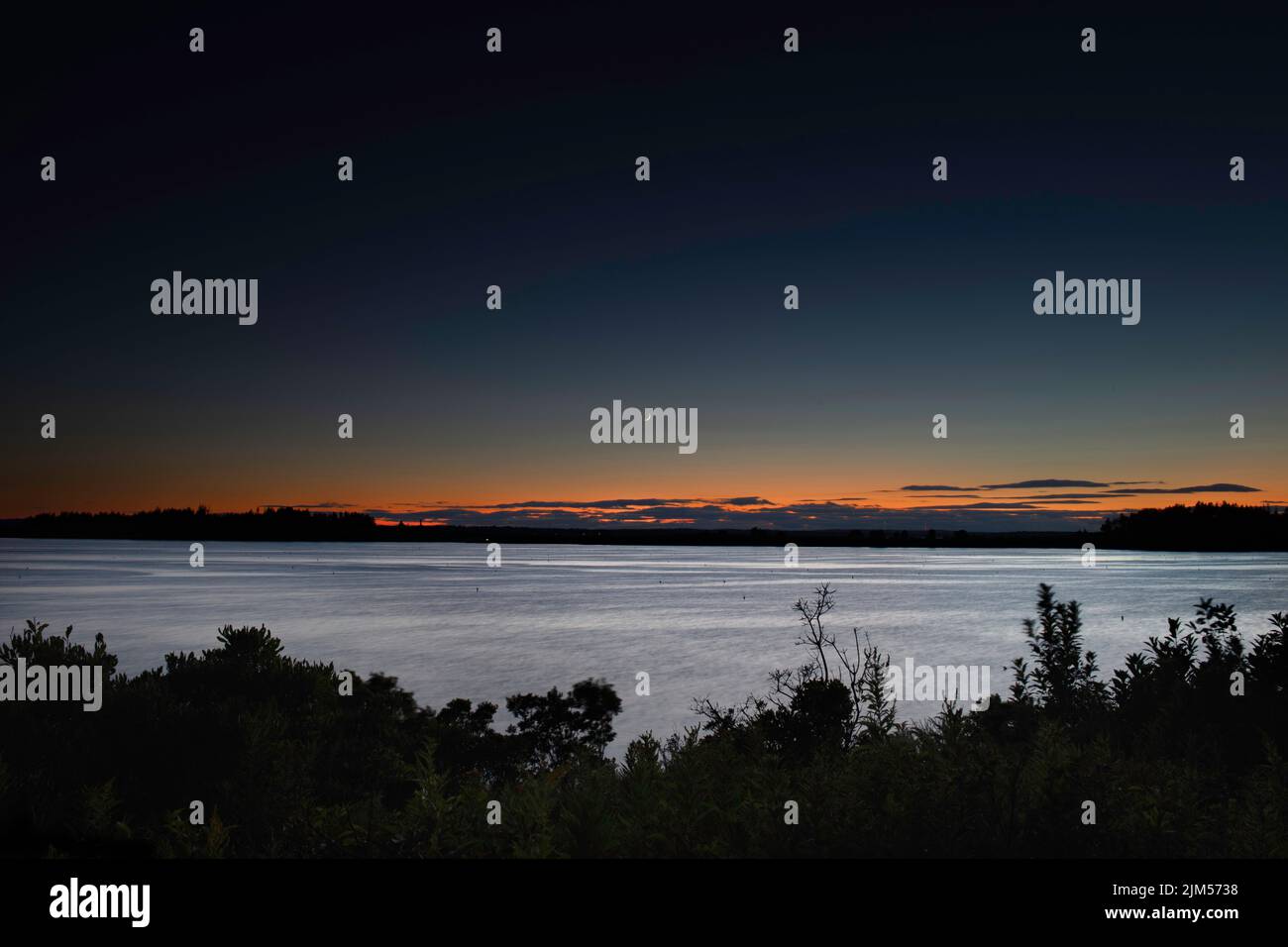 July 30 2022.  Barnes Island.  Post sunset view from Barnes Island.   Showing Whaleboat Island and waxing crescent moon.  Casco Bay, Maine Stock Photo