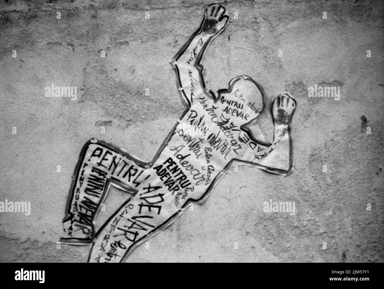 Bucharest, Romania, January 1990. An outline of a dead person placed on the wall of a building in the University Square, one of the key points of the Romanian anticommunist revolution of December 1989. His body is covered with the words '(Dead) for the truth'. Stock Photo