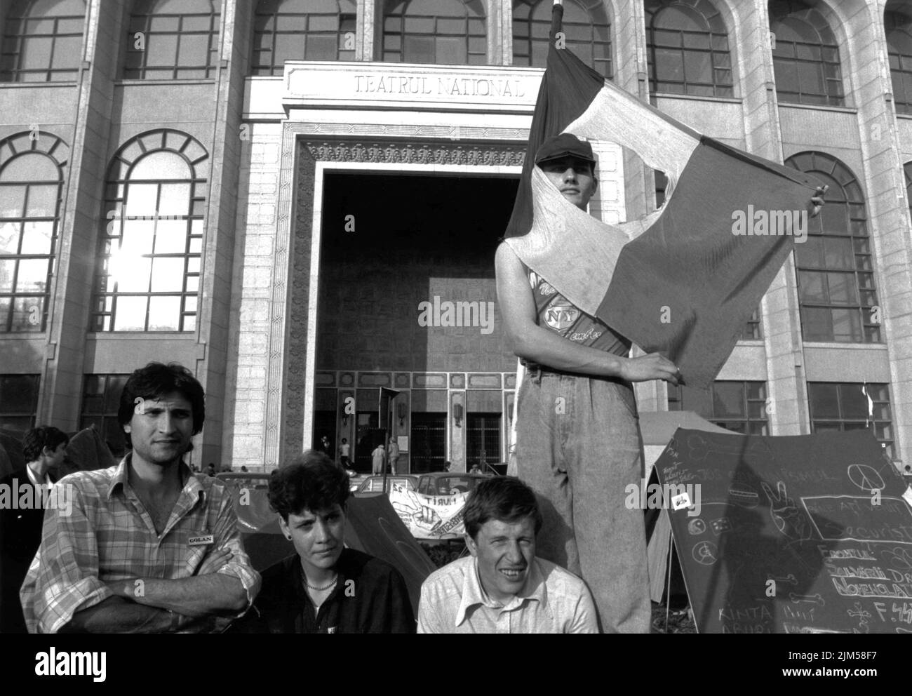 Bucharest, Romania, May 1990. 'Golaniada', a major anti-communism protest  in the University Square following the Romanian Revolution of 1989. People would gather daily to protest the ex-communists that took the power after the Revolution. In this picture, a young man is holding the Romanian flag with the Socialist emblem cut off, an anti-communist symbol during the revolution. Stock Photo
