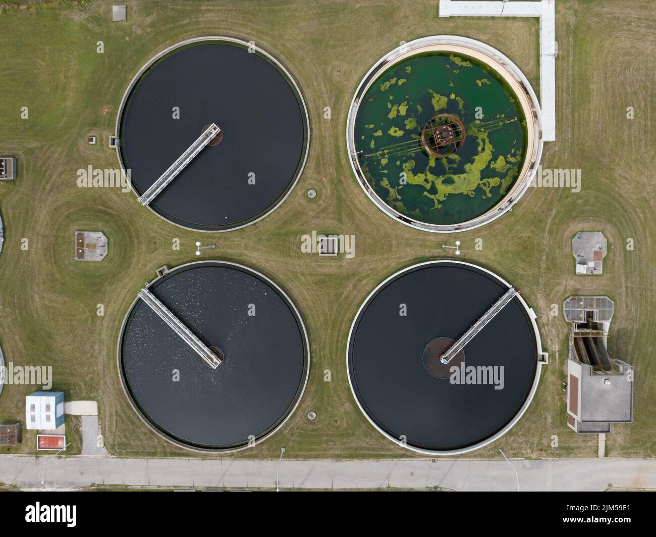 A direct overhead aerial view above a water, sewage treatment plant, centred above four round sedimentation tanks. Stock Photo