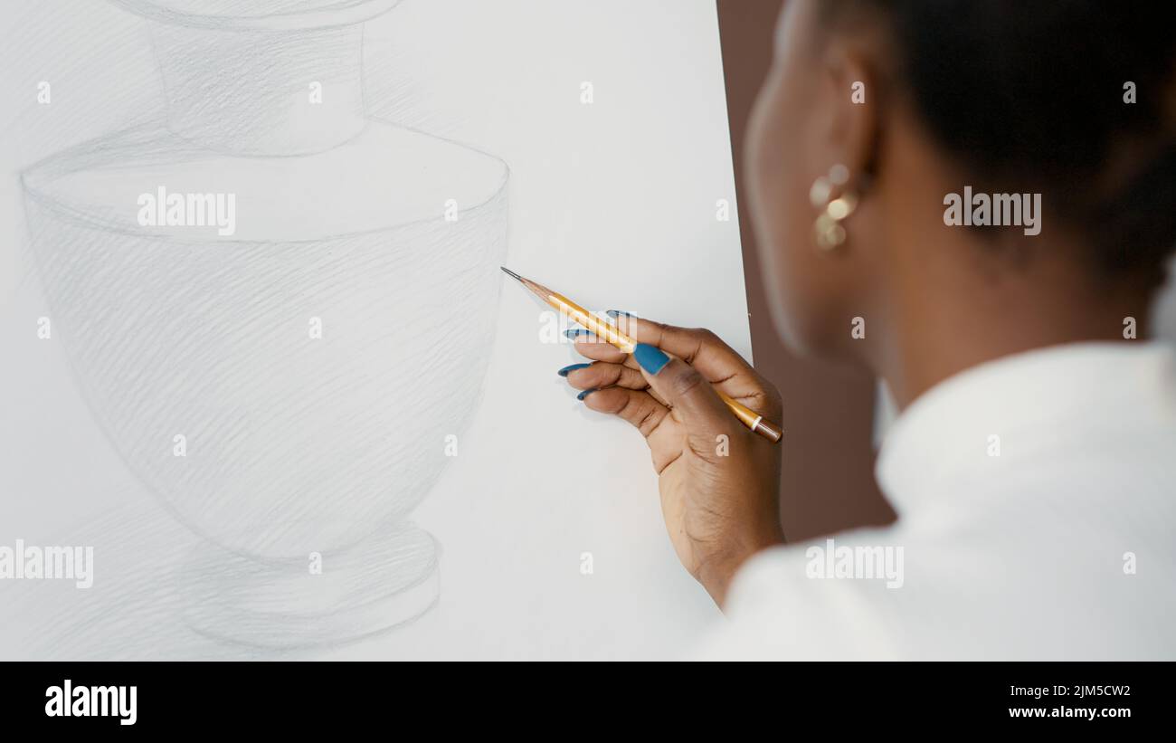Young student drawing vase design on white canvas and easel in art ...