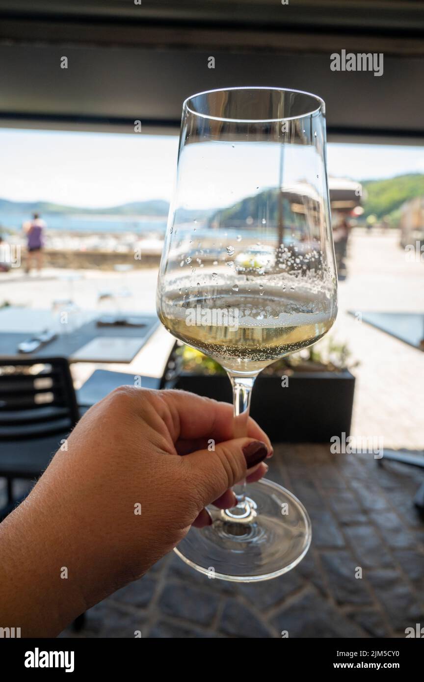 Drinking of txakoli or chacolí slightly sparkling very dry white wine produced in Spanish Basque Country, served in restaurant in Getaria fisherman's Stock Photo