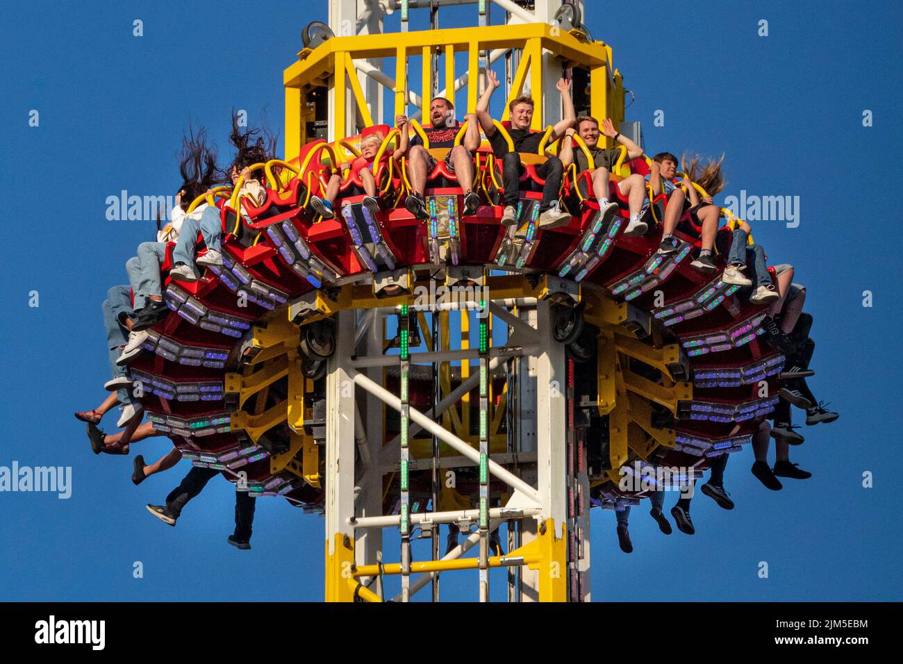 Cranger Kirmes, Herne, NRW, Germany, 04th Aug 2022. Excited people high up on the 'Hangover Tower', just as it drops rapidly. Visitors enjoy the many attractions, roller coasters, beer halls, carousels and more at the Cranger Kirmes fun fair soft opening ahead of the official opening ceremony tomorrow. This is the first time it takes place since Covid restrictions took hold in 2020. The third largest fun-fair in Germany, and largest in Germany's most populous state NRW, usually attracts 4m  visitors over 10 days. It has a long tradition with fairs having taken place on the site since the earl Stock Photo