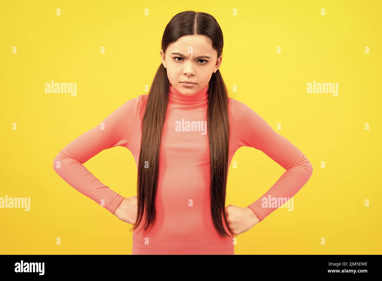 angry kid with long hair on yellow background, anger Stock Photo