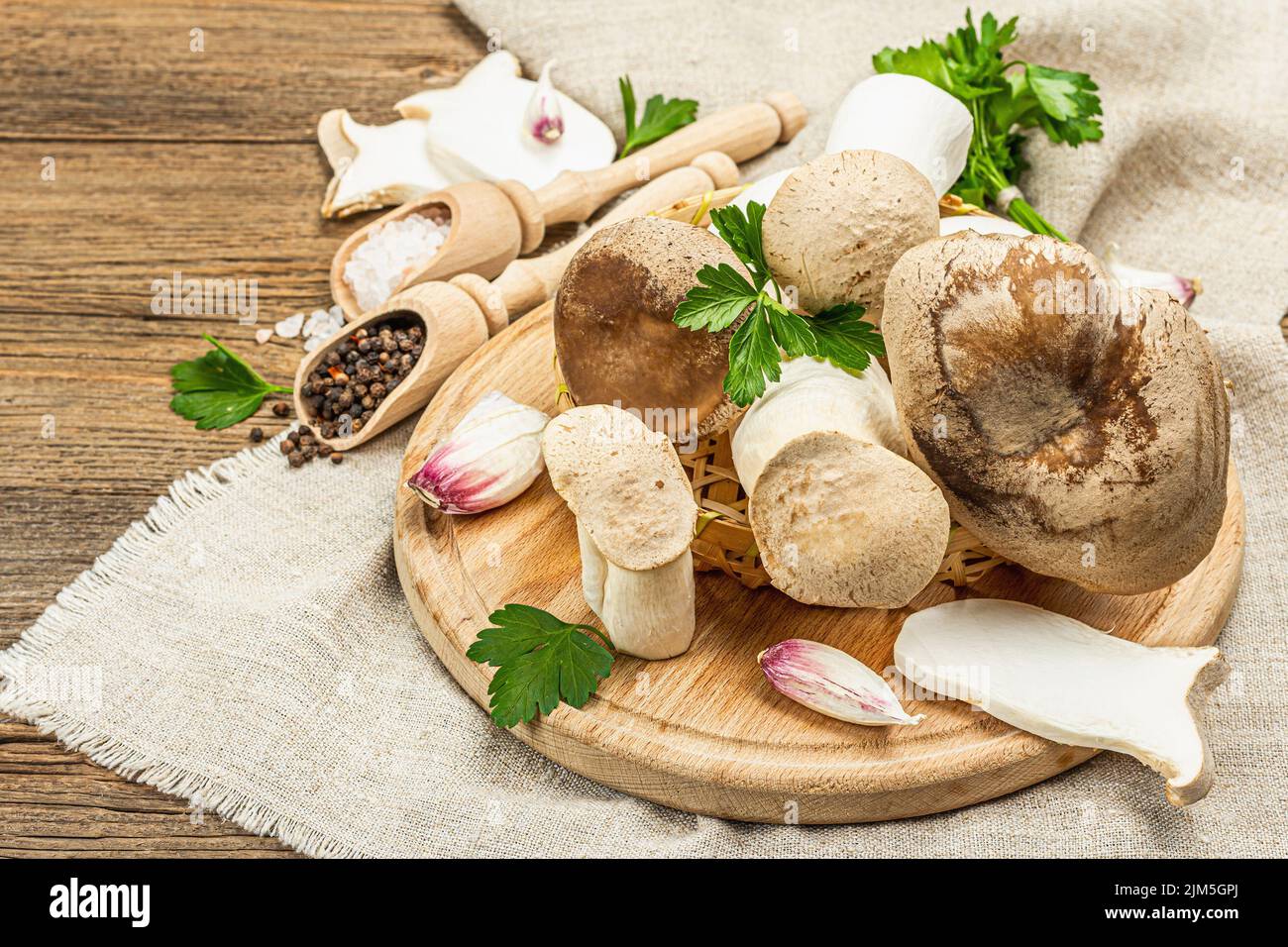Fresh Pleurotus eryngii mushrooms on wooden background. Raw king oyster or eringi with spices