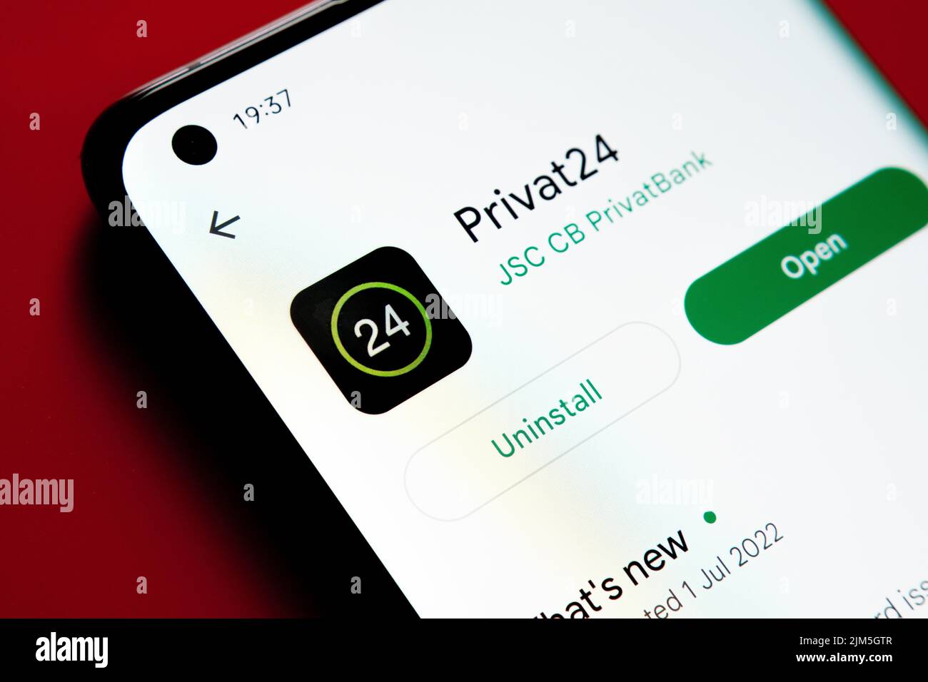 Privat24 app seen in Google Play Store on the smartphone screen placed on red background. Close up photo with selective focus. Stafford, United Kingdo Stock Photo
