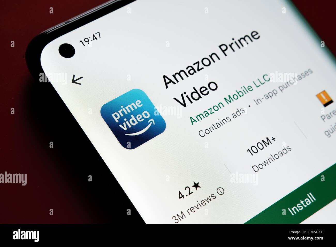 amazon prime video app seen in Google Play Store on the smartphone screen placed on red background. Close up photo with selective focus. Stafford, Uni Stock Photo