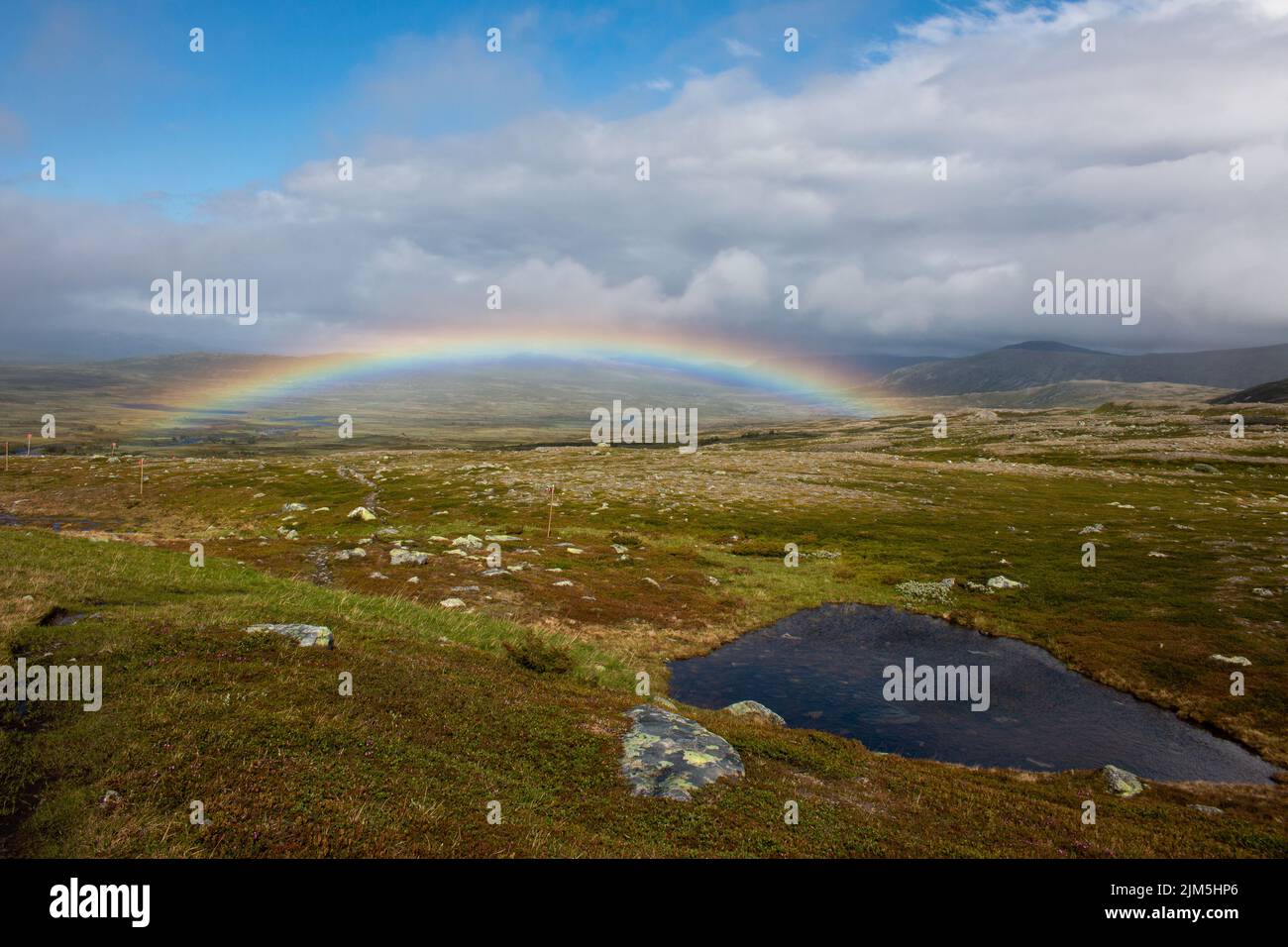 A full rainbow above a hiking trail between Helags Mountain Station and Valastugan mountain hut, Sweden Stock Photo