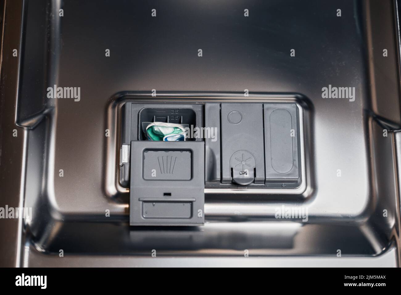 A colorful washing capsule in a dishwashing machine dispenser Stock