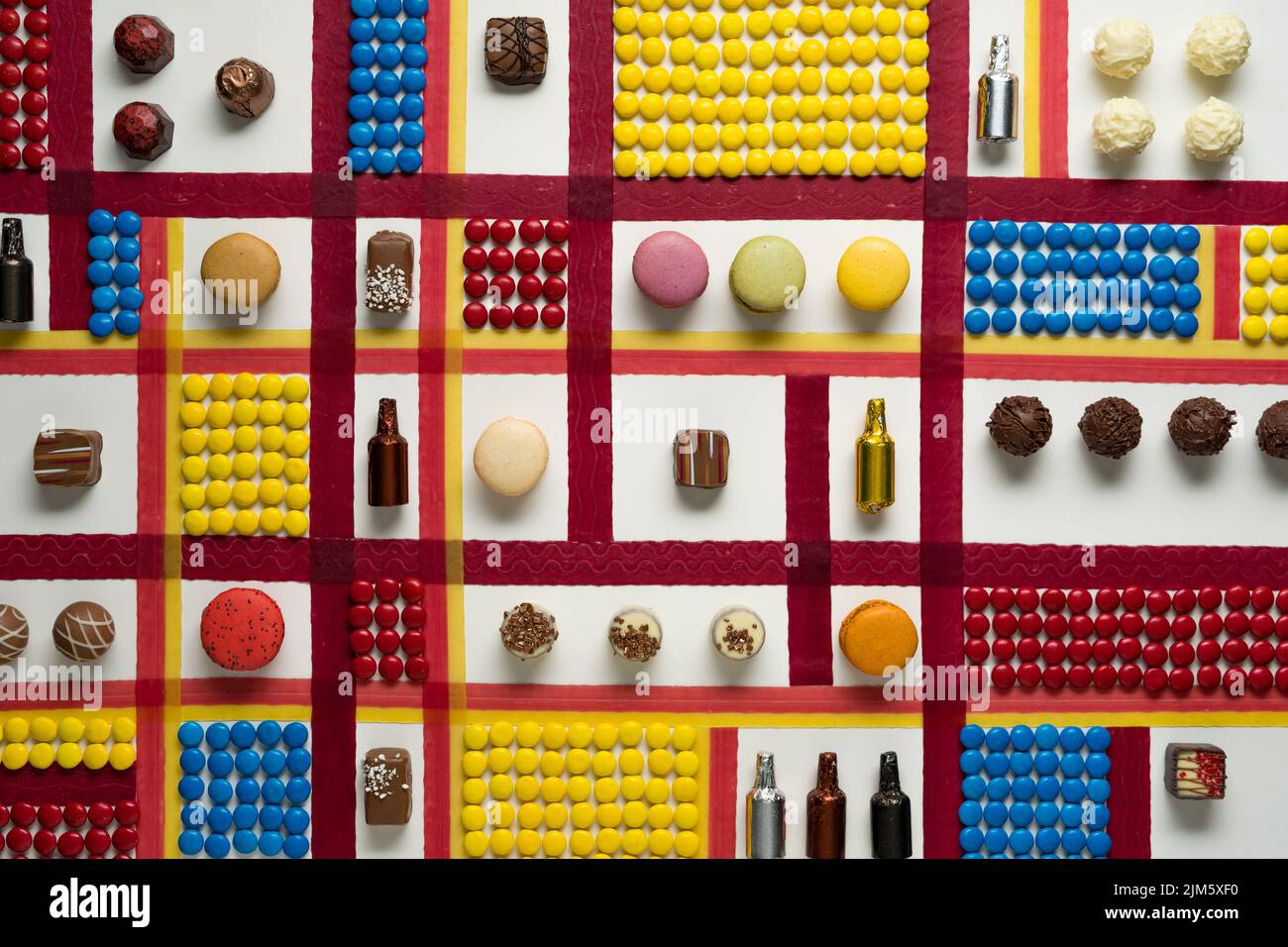 A top view of candy artwork in Mondrian style with red, blue, and yellow squares of button-shaped chocolates Stock Photo