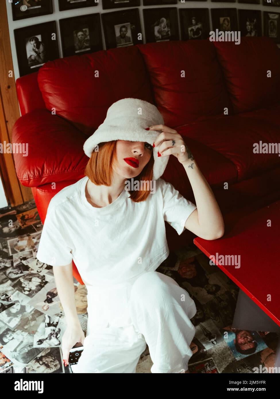 A vertical shot of a Caucasian girl in all white with red lipstick posing in a movie theater Stock Photo