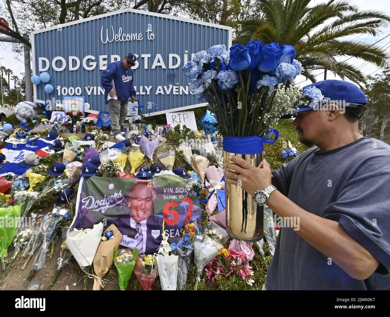 Los Angeles, United States. 04th Aug, 2022. Dodger fans Rubin Castellanos and Peter Castellanos (R) place blue roses on a makeshift memorial at the entrance of Dodger Stadium on Thursday, August 4, 2022. Vin Scully, the legendary Los Angeles Dodgers broadcaster died Tuesday at 94. Photo by Jim Ruymen/UPI Credit: UPI/Alamy Live News Stock Photo