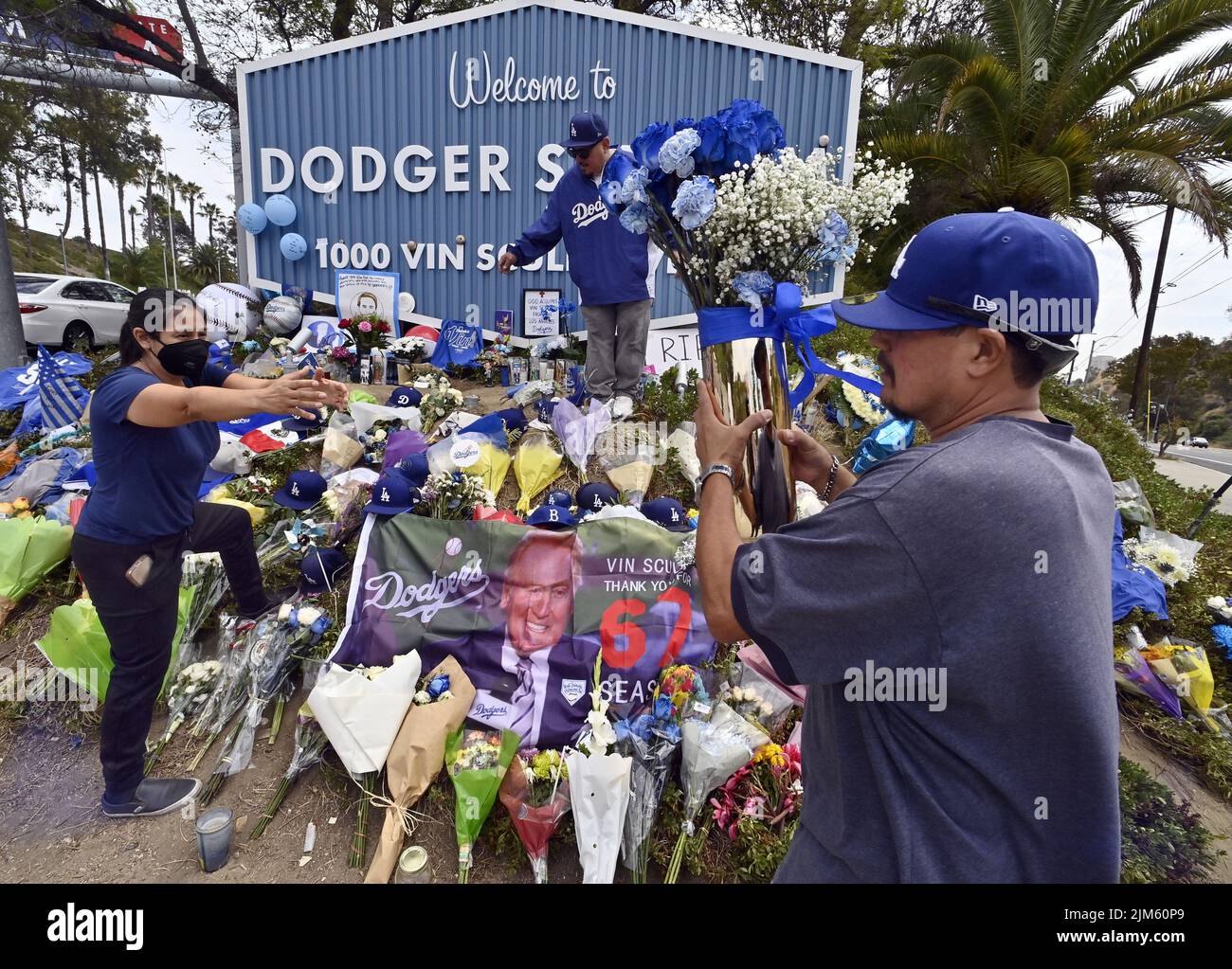 Los Angeles, United States. 04th Aug, 2022. Dodger fans Jackie Perez, Rubin Castellanos and Peter Castellanos (L-R) place blue roses on a makeshift memorial at the entrance of Dodger Stadium on Thursday, August 4, 2022. Vin Scully, the legendary Los Angeles Dodgers broadcaster died Tuesday at 94. Photo by Jim Ruymen/UPI Credit: UPI/Alamy Live News Stock Photo