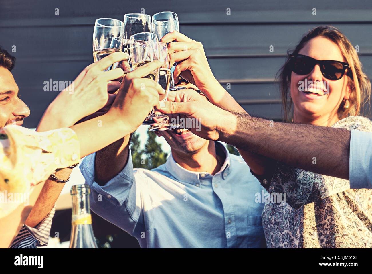 Cheerful young friends having a celebratory toast in the resort backyard - happy people clinking champagne flute glasses - people and alcohol lifestyl Stock Photo
