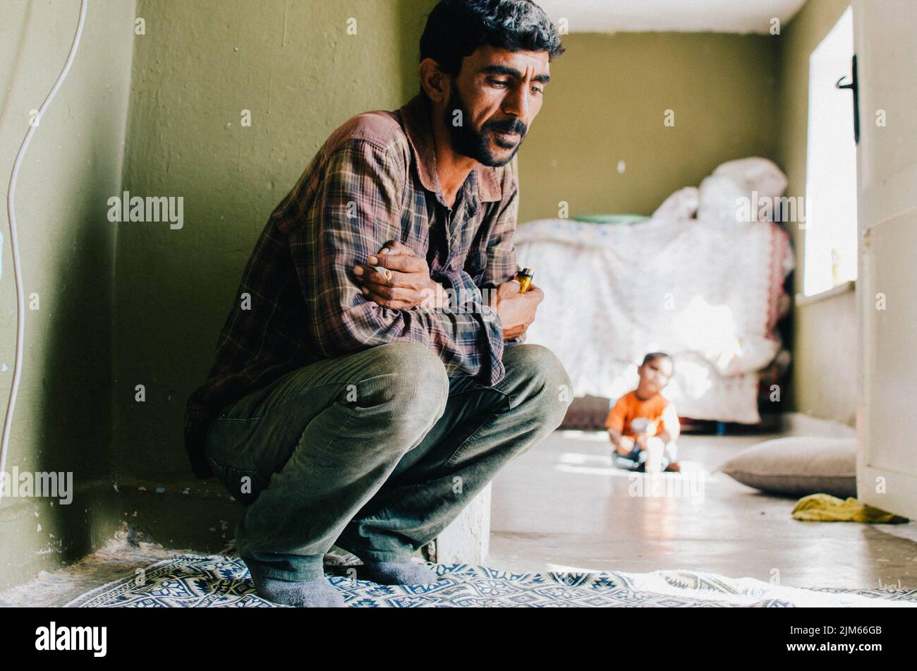 A view of a turkish man sitting on the floor in an apartment and a ...