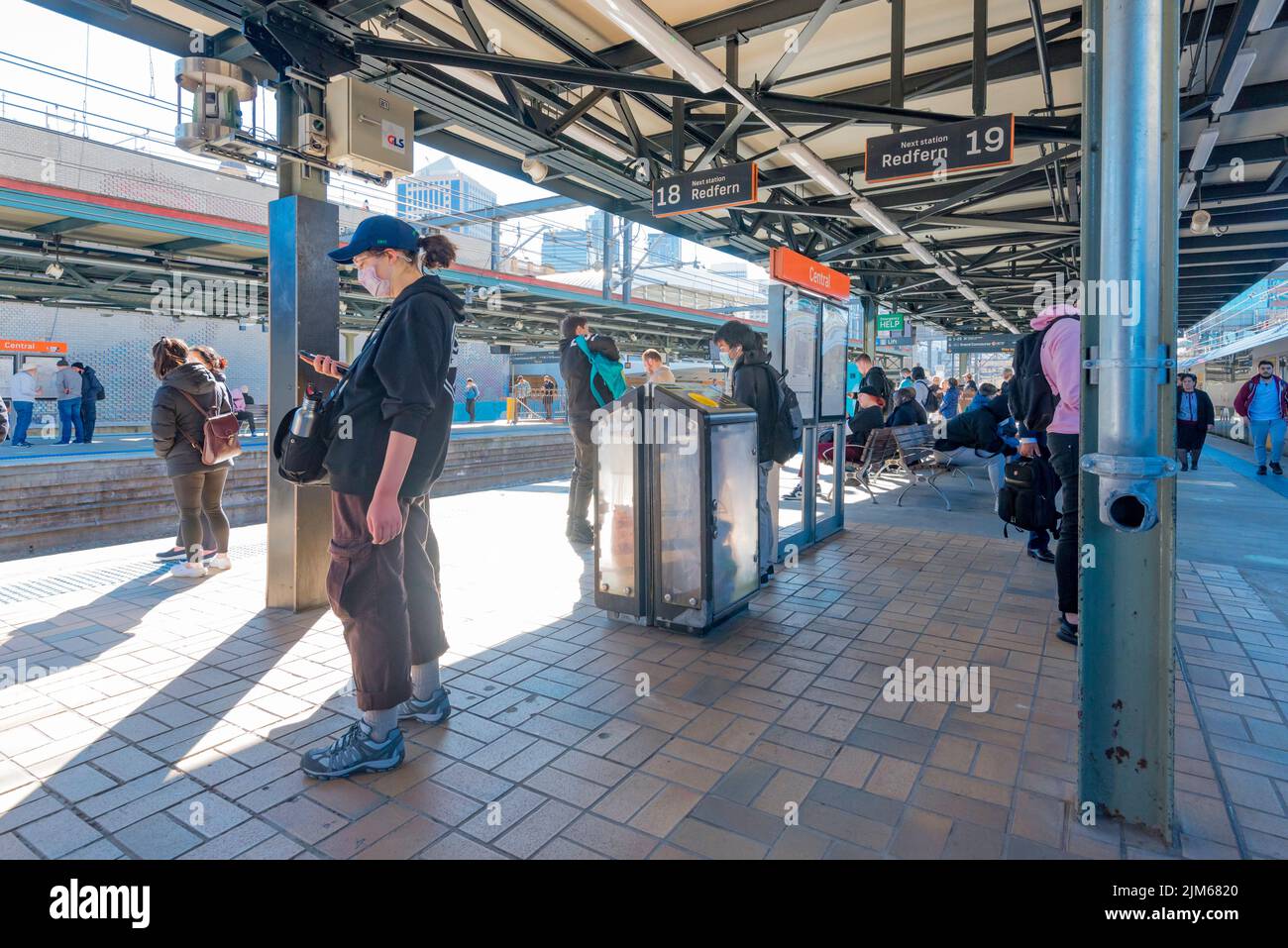 June 2022: People waiting, some wearing masks, during the day on platforms 18 and 19 at Central Station in Sydney, New South Wales, Australia Stock Photo