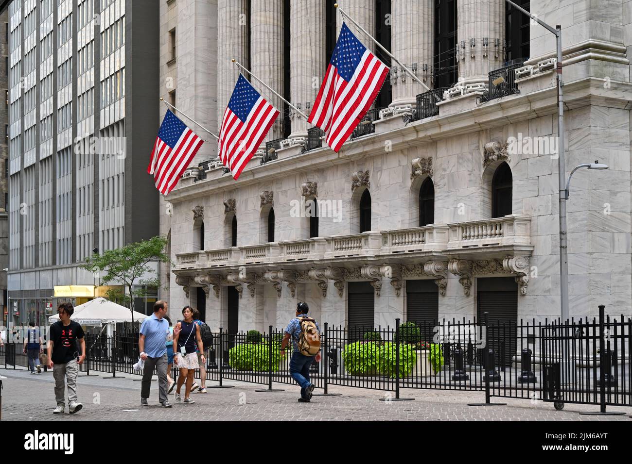 People walk past the New York Stock Exchange (NYSE) on Wall Street in New York. Stock Photo