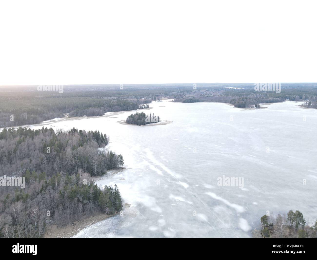 An aerial view of winter forest landscape with ice covered lake and ...