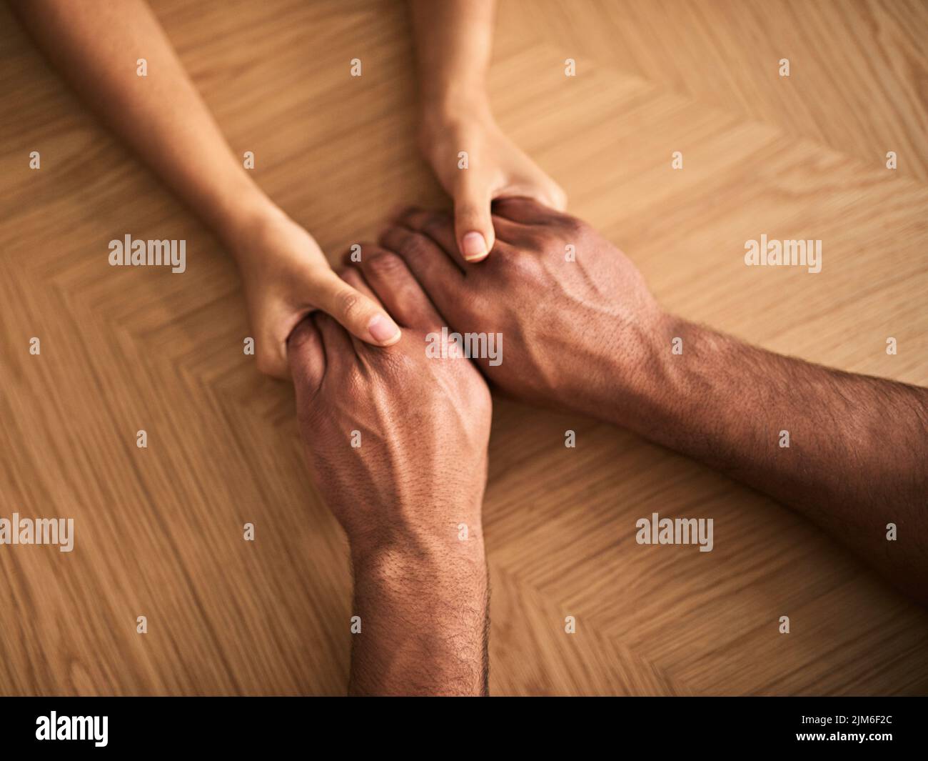 Couple holding hands showing love, romance and support while sitting at a table from above. Top view of a loving husband and wife sharing affectionate Stock Photo