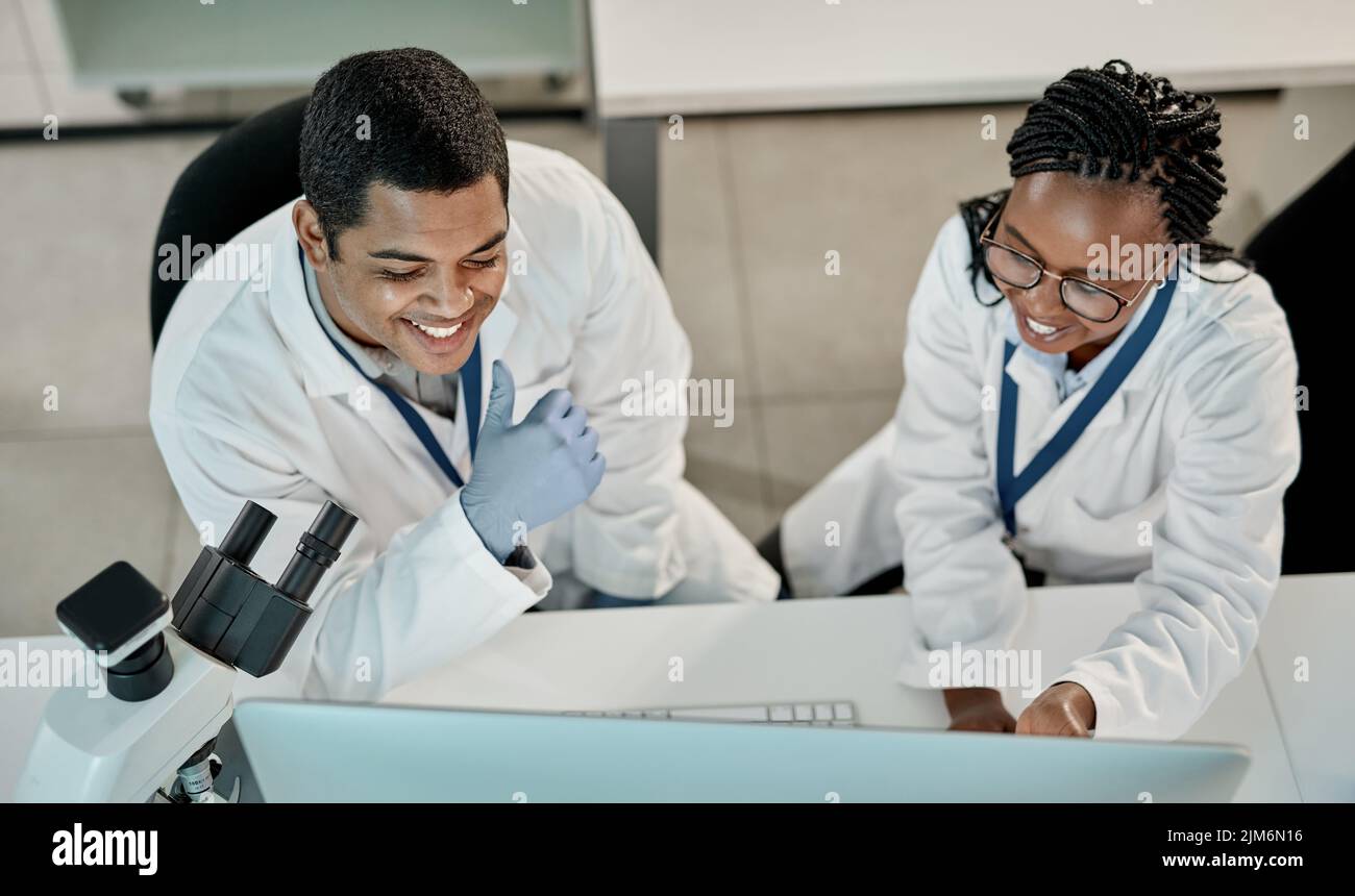 Getting things done in the lab. two scientists working together on a computer in a lab. Stock Photo