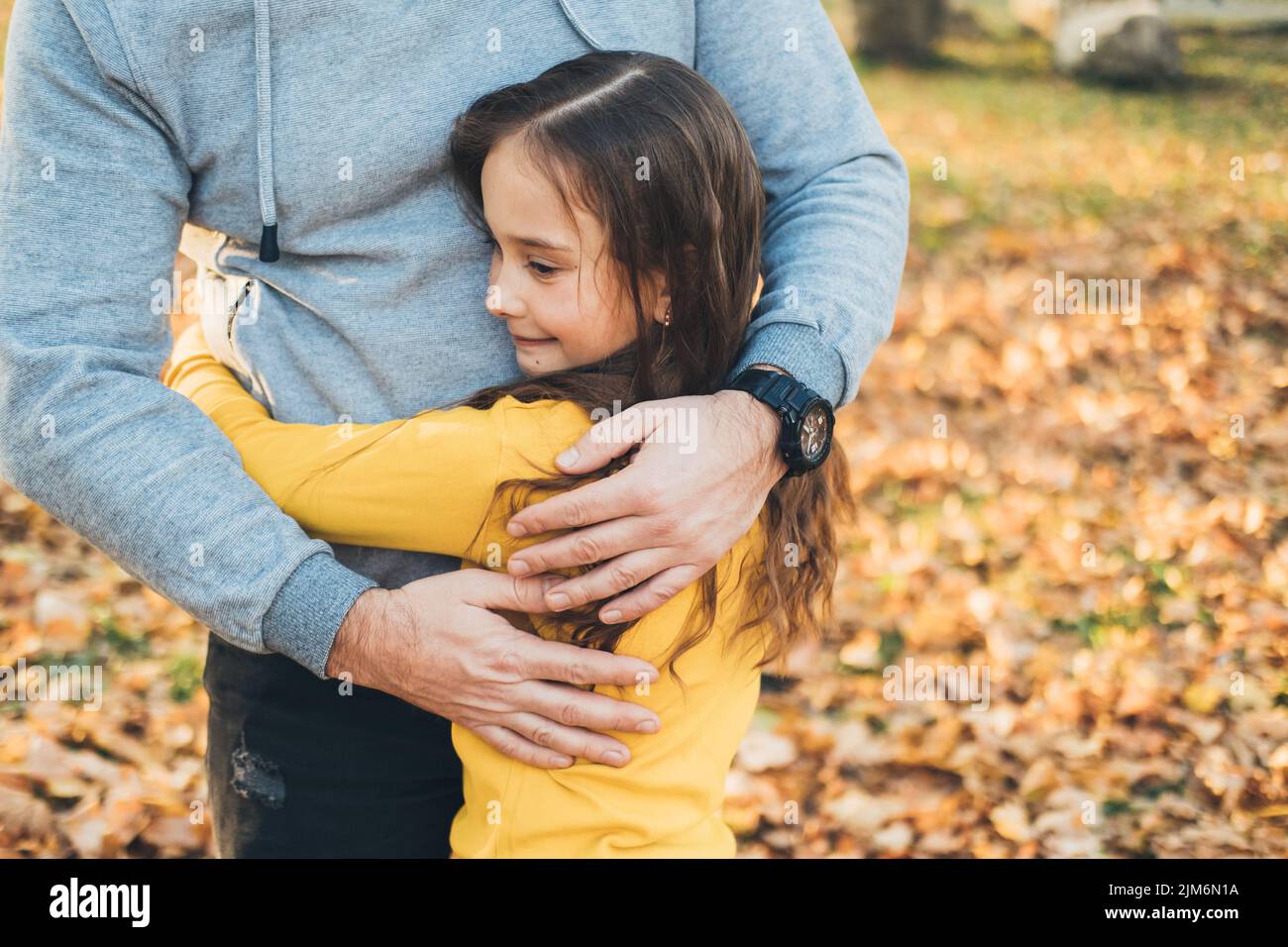 Close-up portrait of daughter hugging her father outside in the park. Happy loving family. Parent, child. Happy family, childhood.R ejoice and have Stock Photo