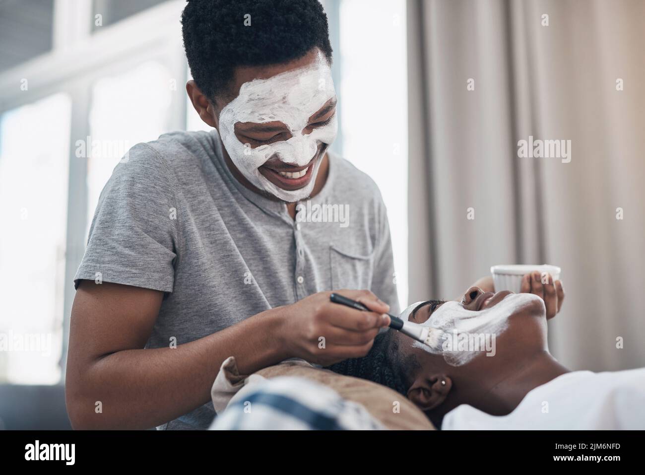 Quarantine dates take a bit of creativity. a young couple getting homemade facials together at home. Stock Photo