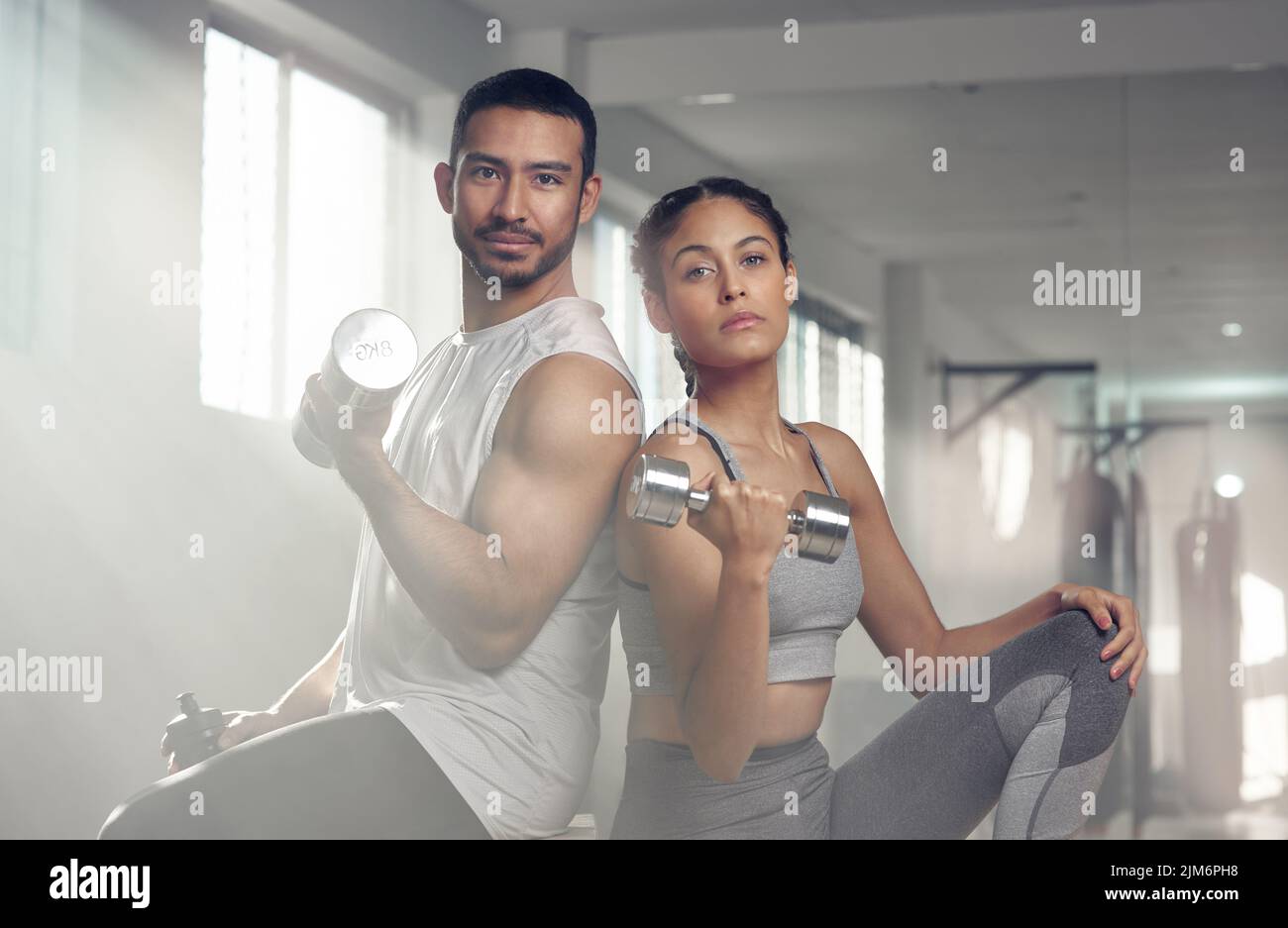 Do a little more and complain a little less. two young athletes holding dumbbells. Stock Photo
