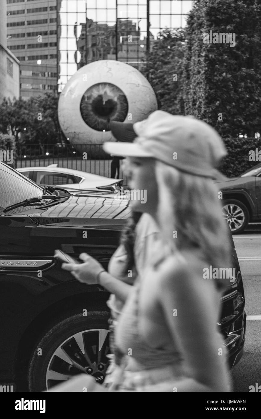 A grayscale shot of cars in Downtown Dallas with blurry females walking on foreground Stock Photo