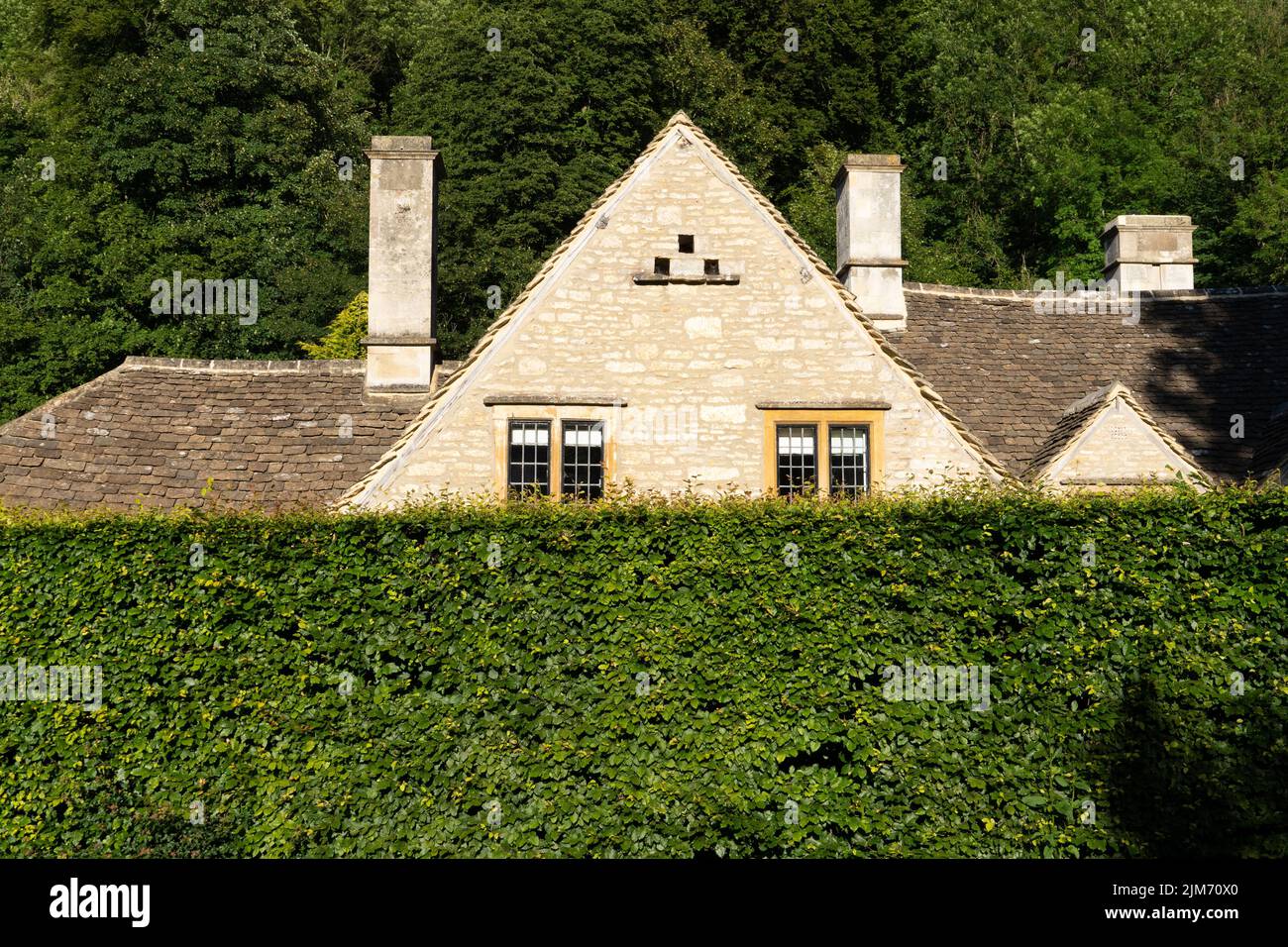 The view of the house roof behind the green hedge. Cotswolds,  England, UK. Stock Photo