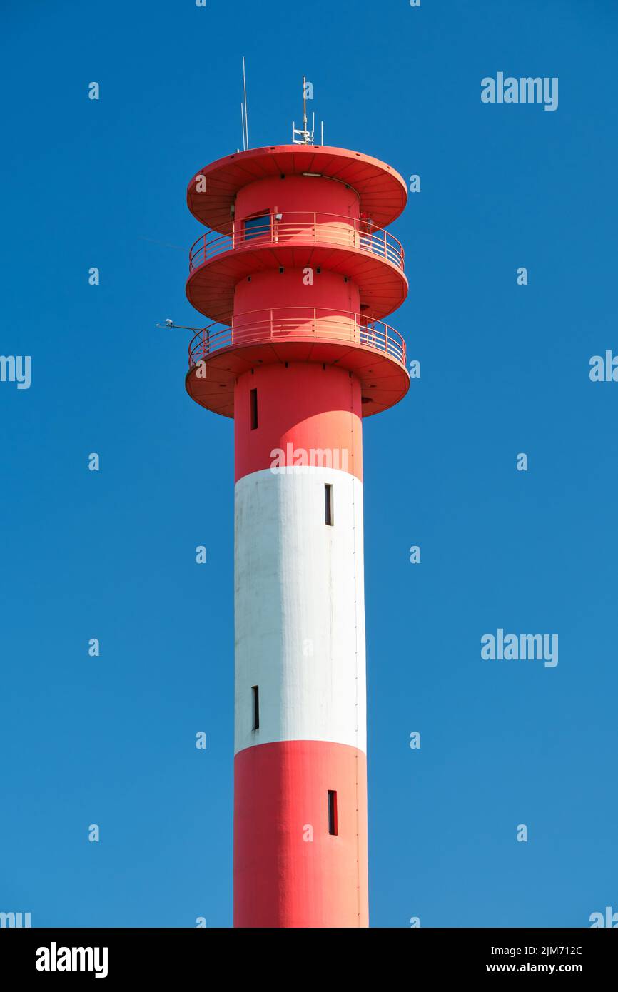 Vertical shot of red and white lighthouse with blue sky in background ...