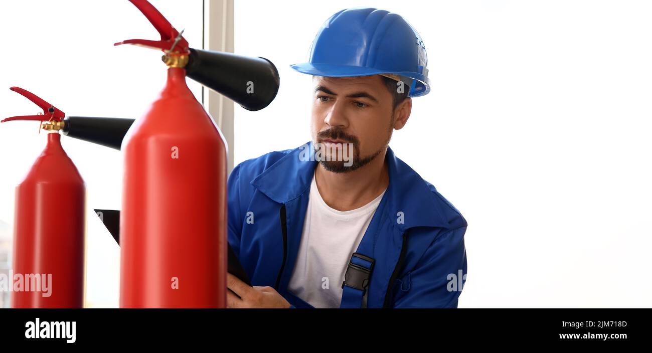 Fire safety specialist inspecting extinguisher in premises Stock Photo