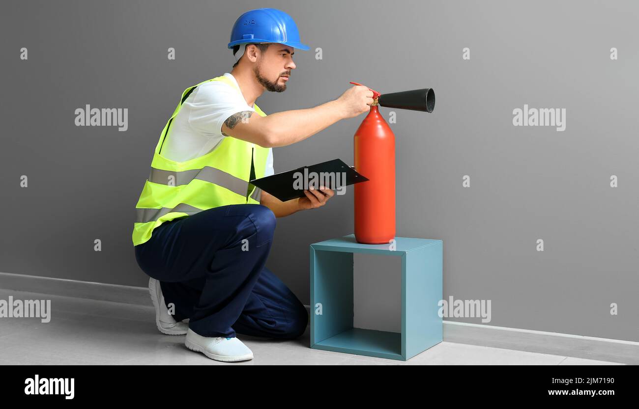 Fire safety specialist inspecting extinguisher in premises Stock Photo