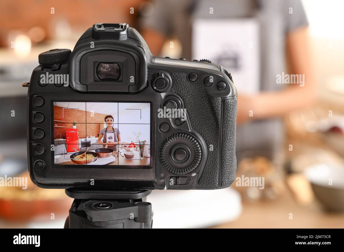 Young woman with cooking book on display of photo camera in kitchen ...