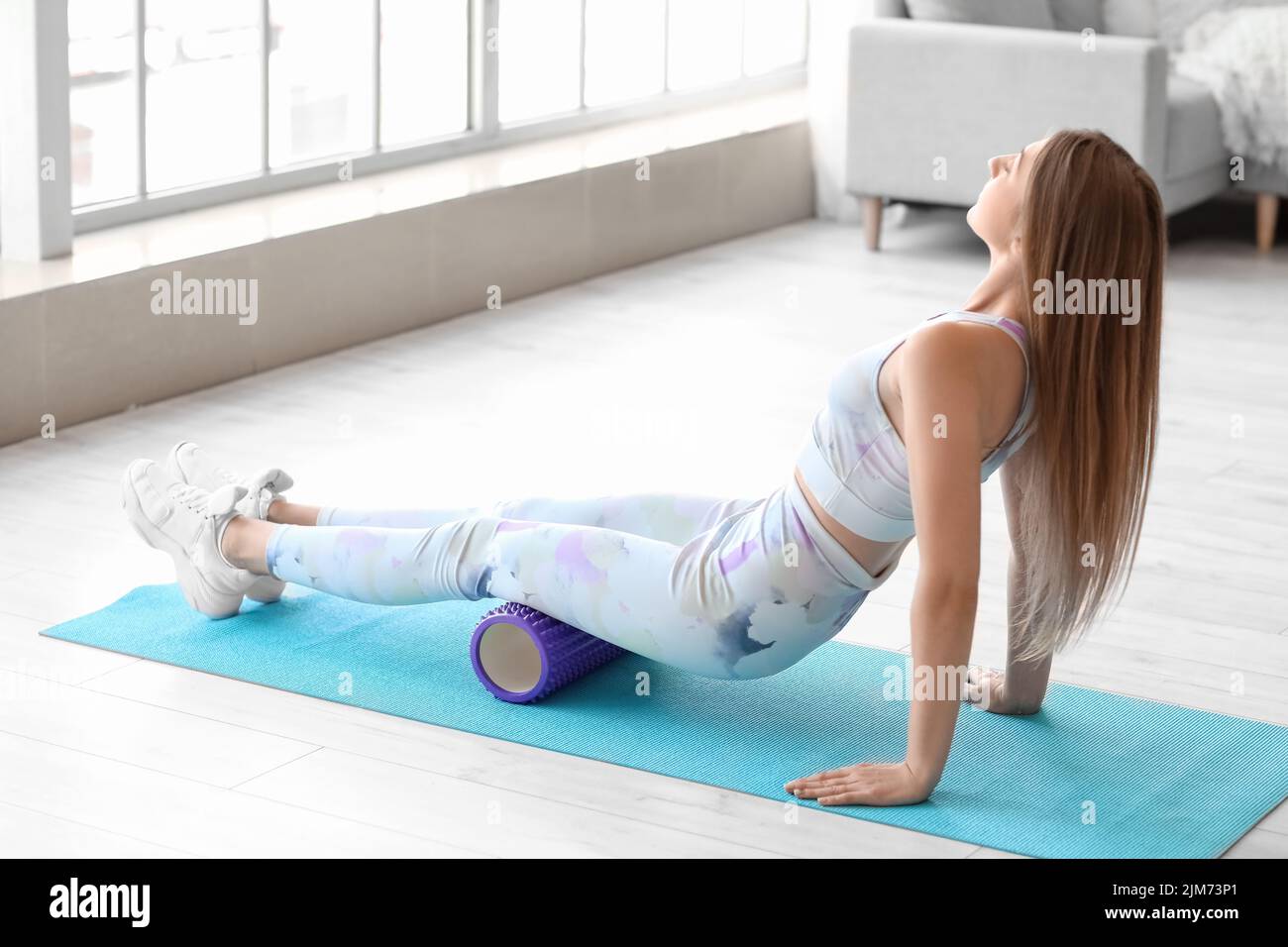 Young woman training with foam roller at home Stock Photo - Alamy