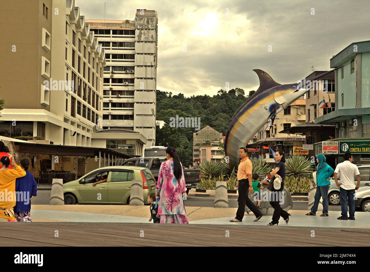 People having leisure time on a seaside platform, in a background of afternoon traffic in Kota Kinabalu, Sabah, Malaysia. Stock Photo