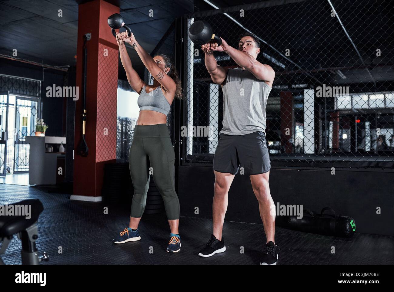 Upping their power and endurance together. two sporty young people exercising with kettlebells in a gym. Stock Photo