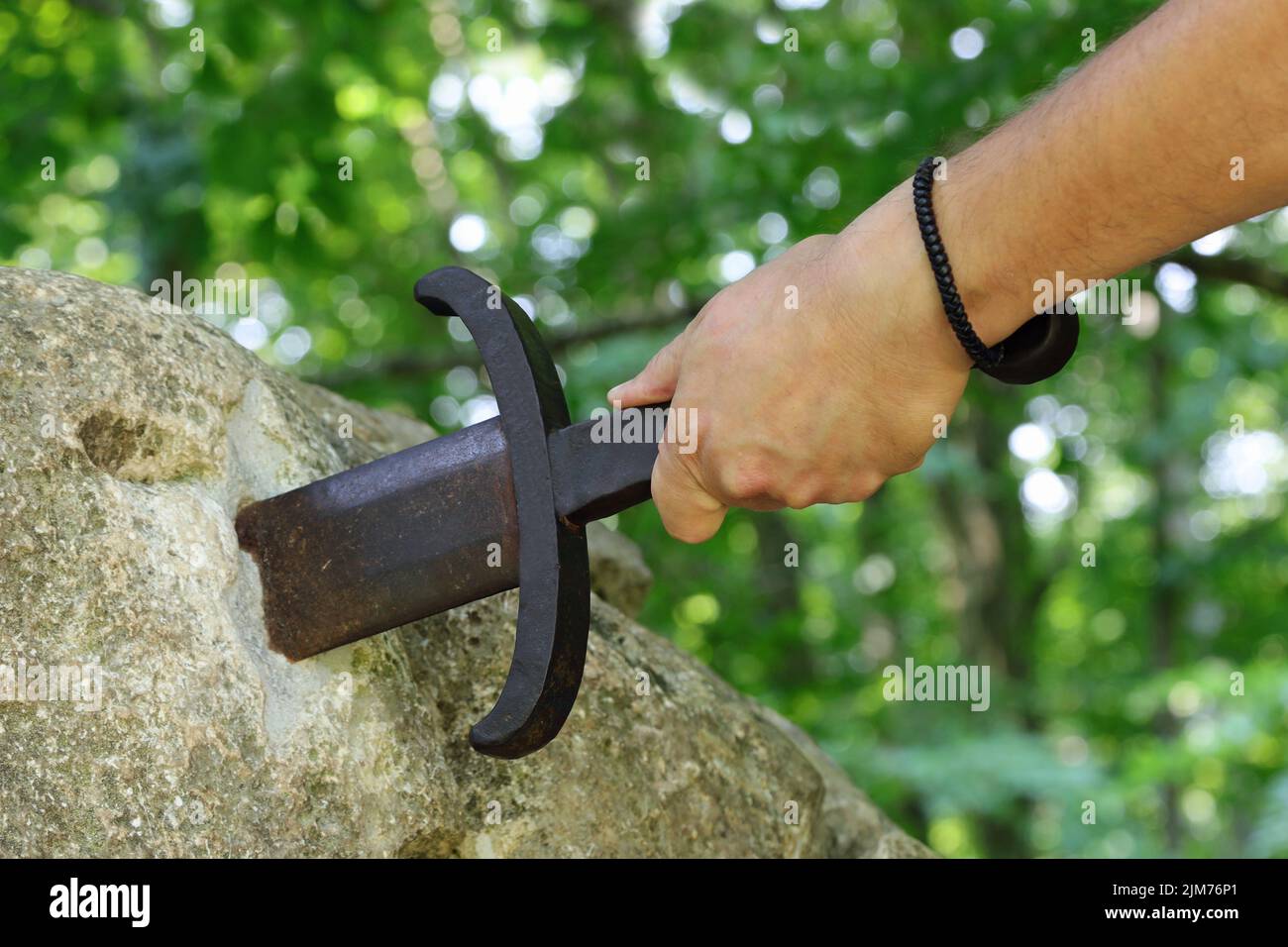 hand of knight and sword in the stone as in the legend of King Arthur Stock Photo