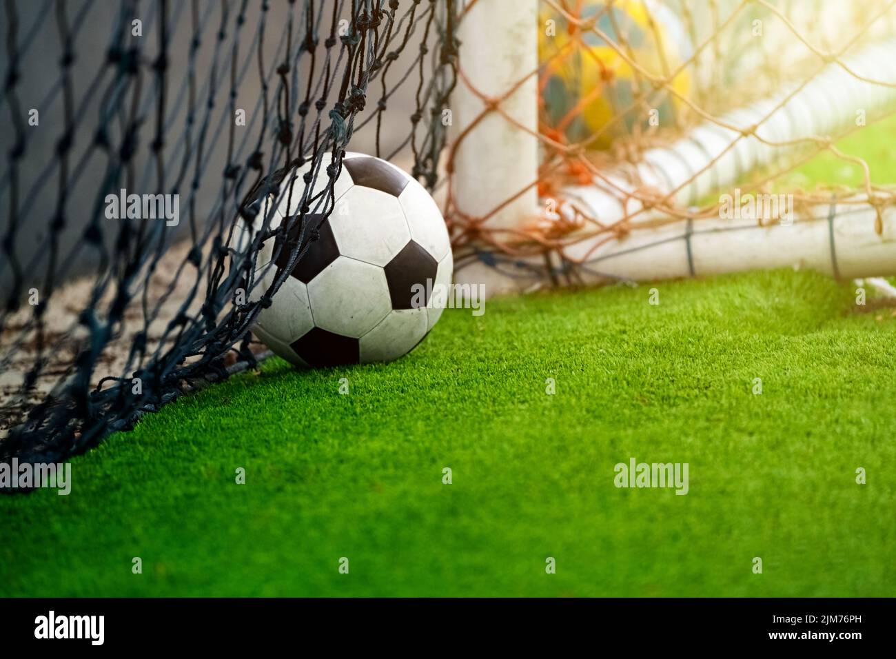 Close up of a football and goal lying on the grass with little sun ray coming through. It reminds us of a world class festival, once every four years Stock Photo