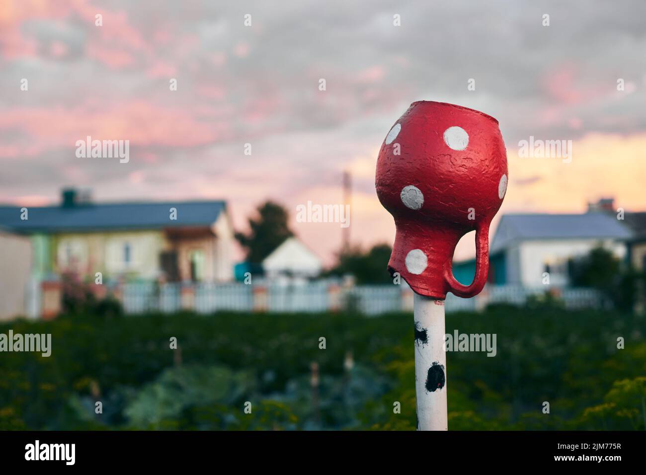 A red ceramic jug on a pole in the countryside in the summer. Rural idyllic scene. Front view. Stock Photo