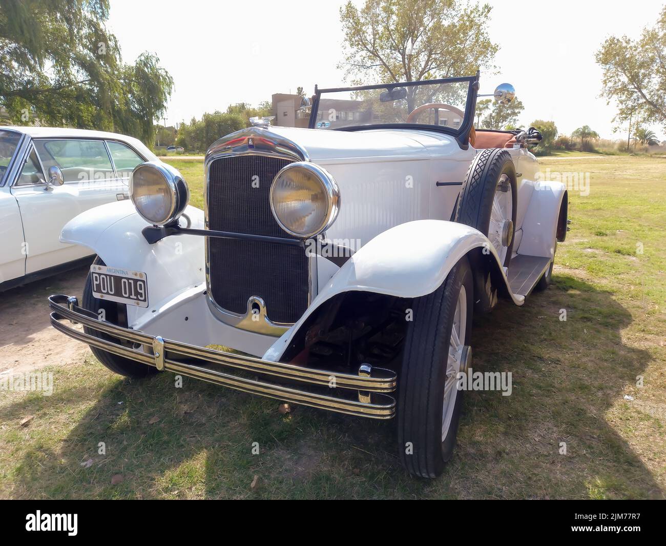 Old white Chrysler Plymouth roadster circa 1930 parked in the countryside. Nature grass and trees background. Classic car show. Stock Photo