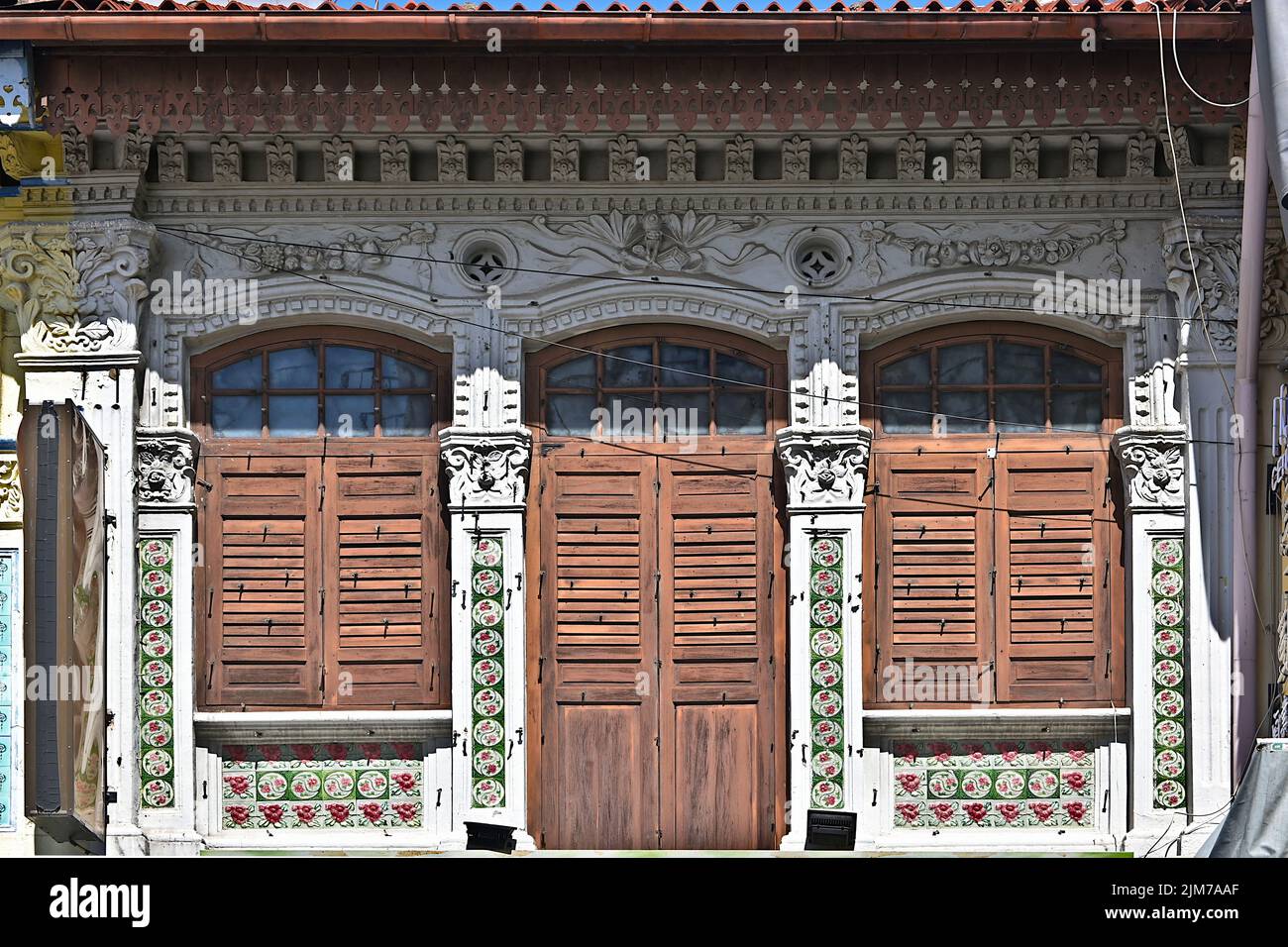 Straits Chinese Peranakan shophouse with brown louvered shutters, ornate columns & decorative plaster motifs Stock Photo