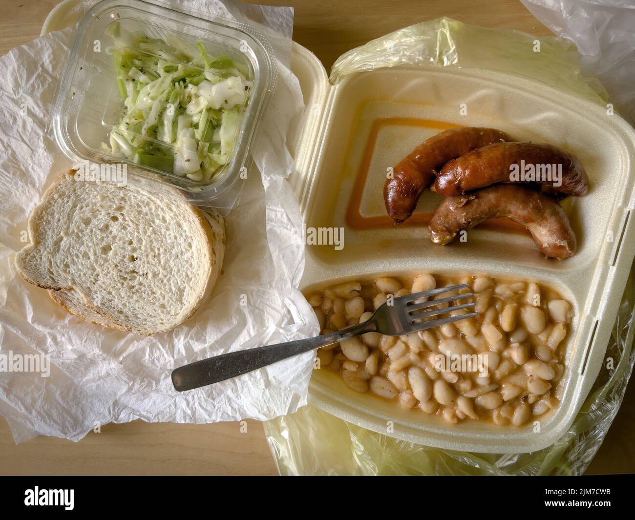 Takeaway food in styrofoam packaging white beans and sausages with